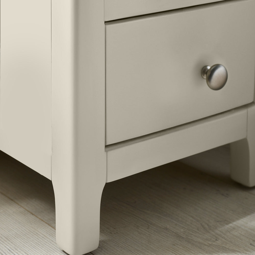 Close-up of bedside leg detailing painted light grey with gentle curve near base on wooden flooring