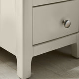 Close-up of bedside leg detailing painted light grey with gentle curve near base on wooden flooring