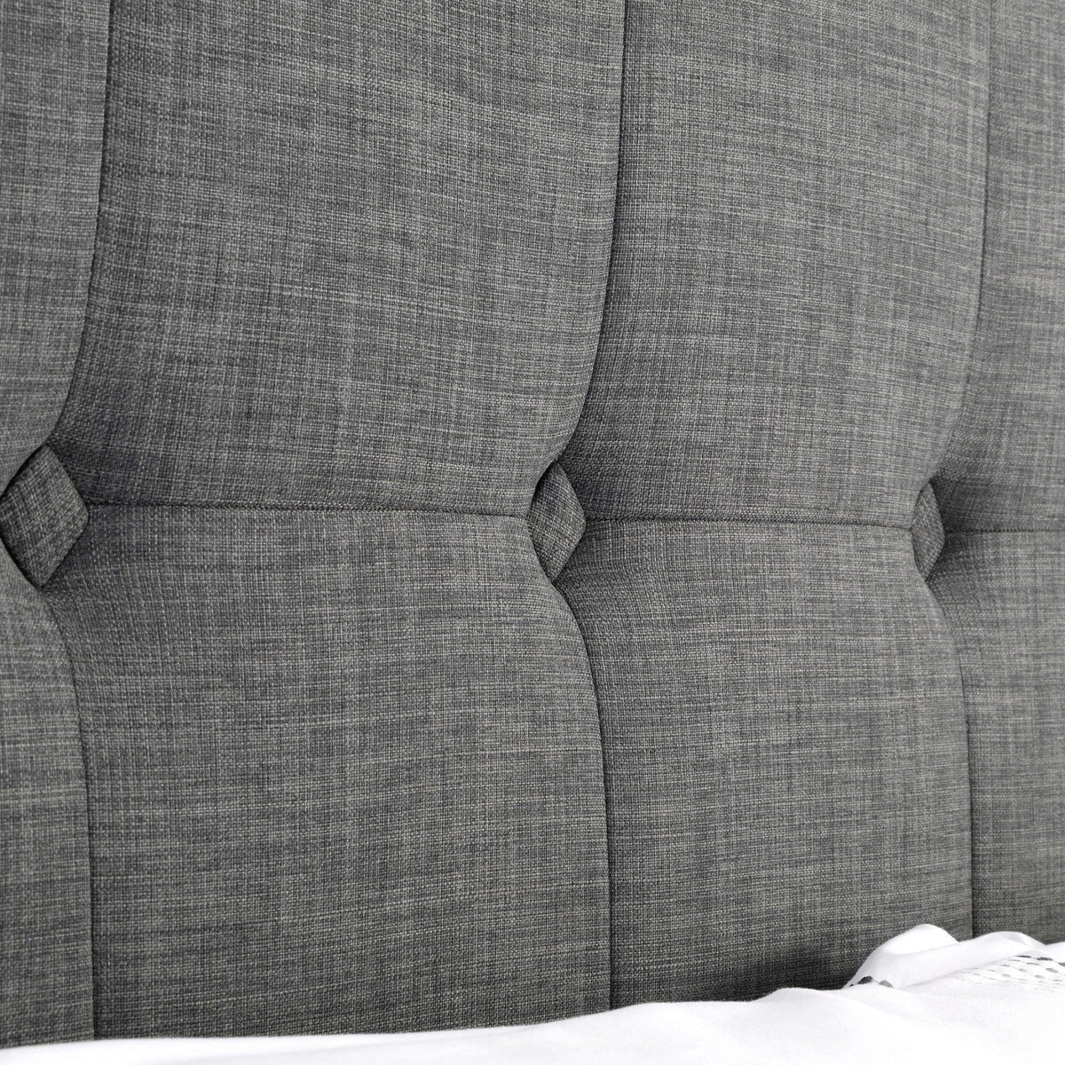 Detail of slate linen king bed headboard with tufted upholstery