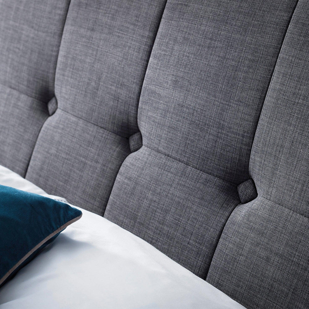 Close view of slate linen ottoman bed headboard with button-tufted detail