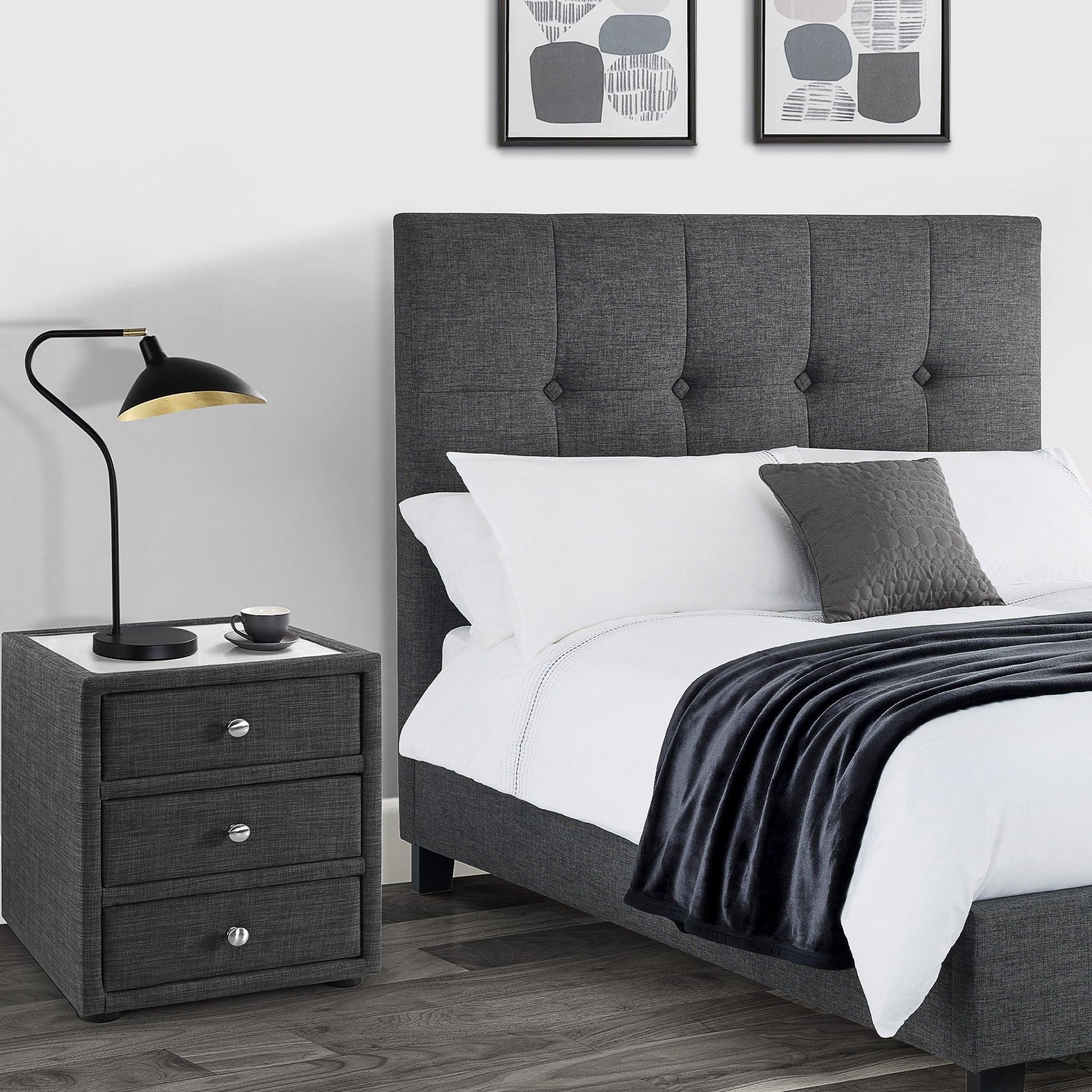 Slate linen three drawer bedside table next to upholstered bed in modern bedroom