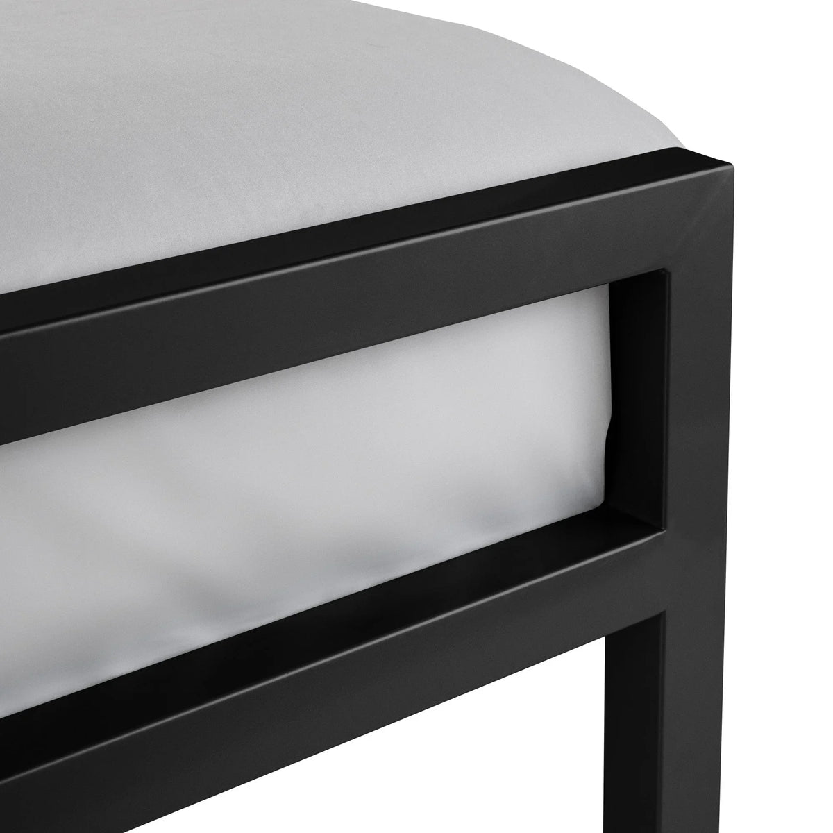 Corner detail of black metal bed frame with white mattress
