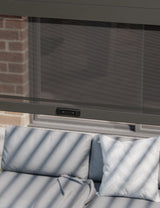 Outdoor sofa with grey cushions under a retractable mesh screen on patio