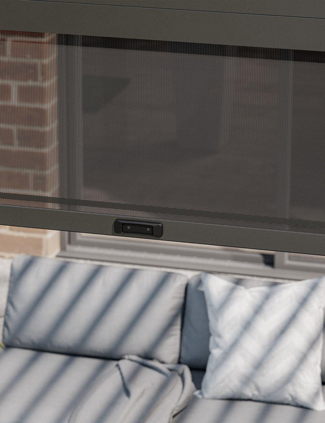 Outdoor sofa with grey cushions under a retractable mesh screen on patio