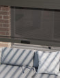 Outdoor sofa with grey cushions under a retractable mesh screen on patio