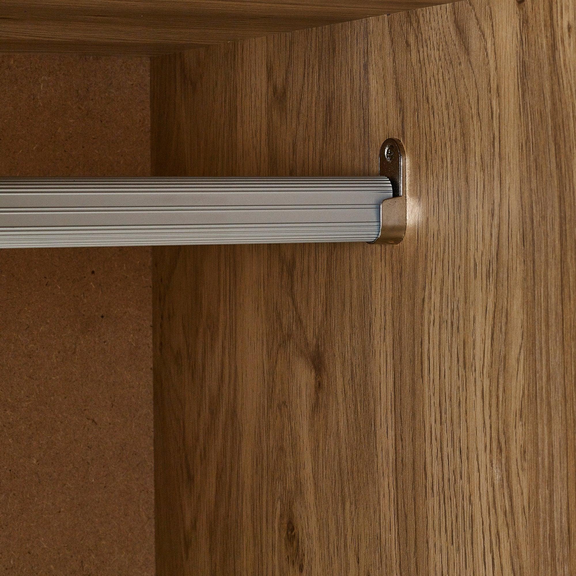 Wardrobe interior showing metal hanging rail and wood effect panel