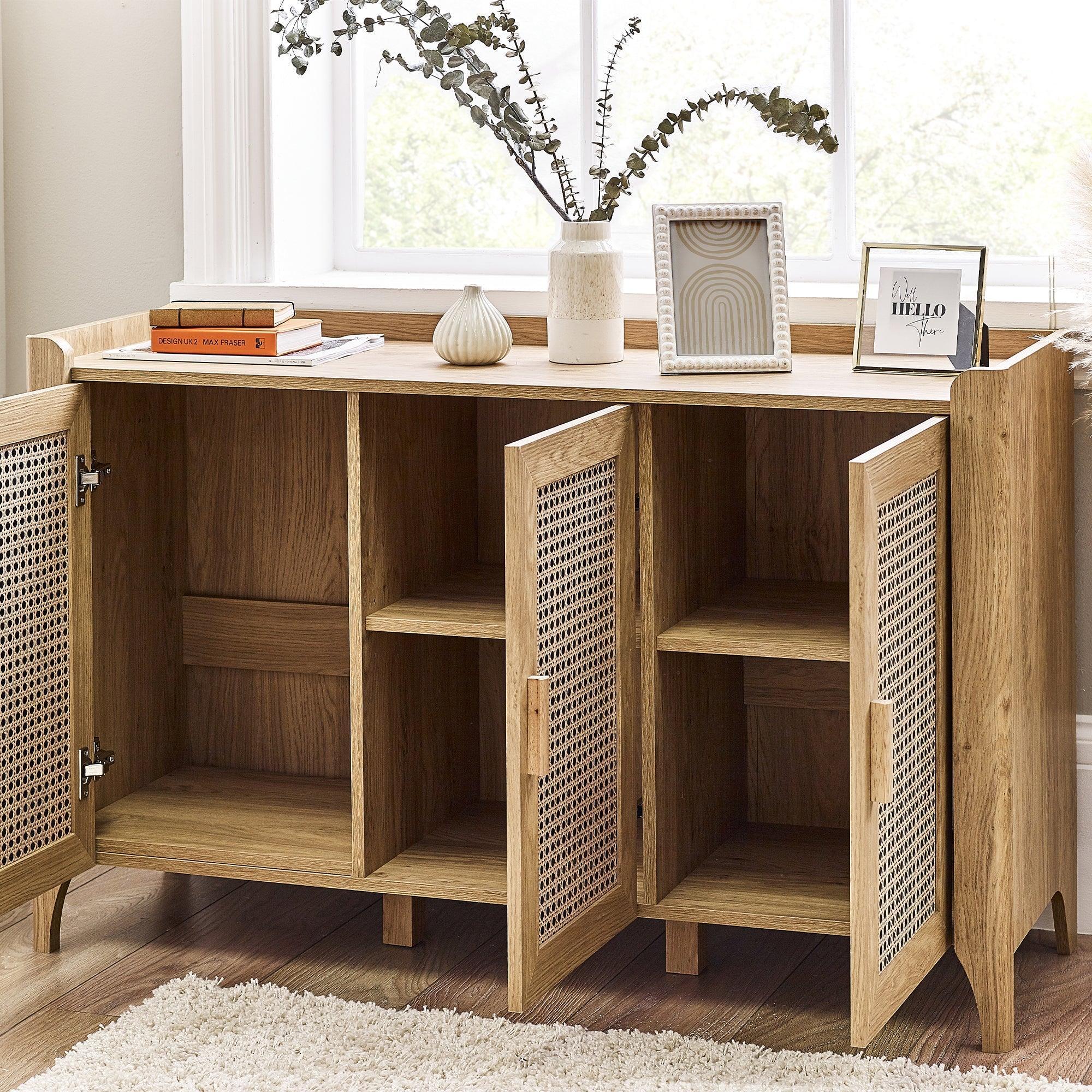Three door rattan effect sideboard with open shelves, styled with decor and books by window