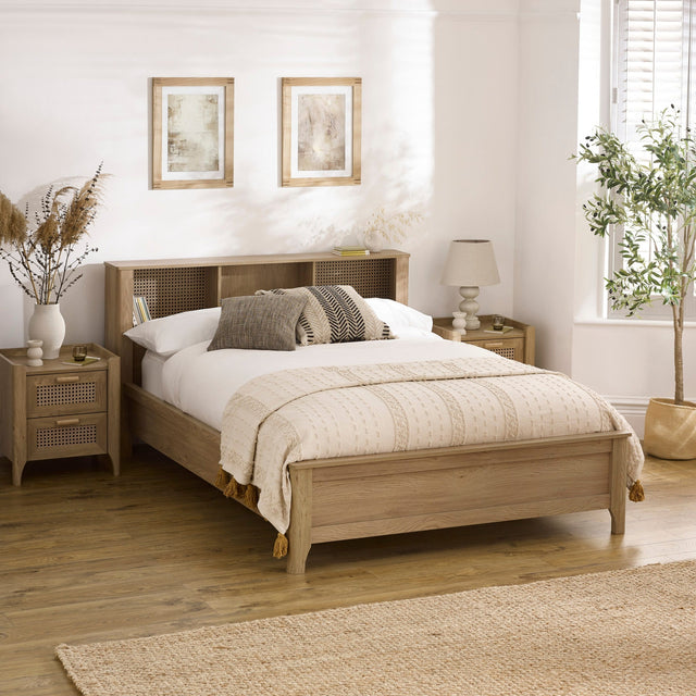 Oak wood bed with built-in shelves in headboard, beige bedding, side tables and botanical decor in room