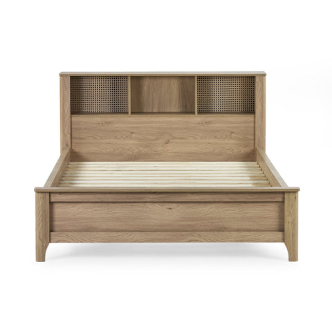 Front view of oak wood bed frame with slatted base and built-in shelving in headboard on white background