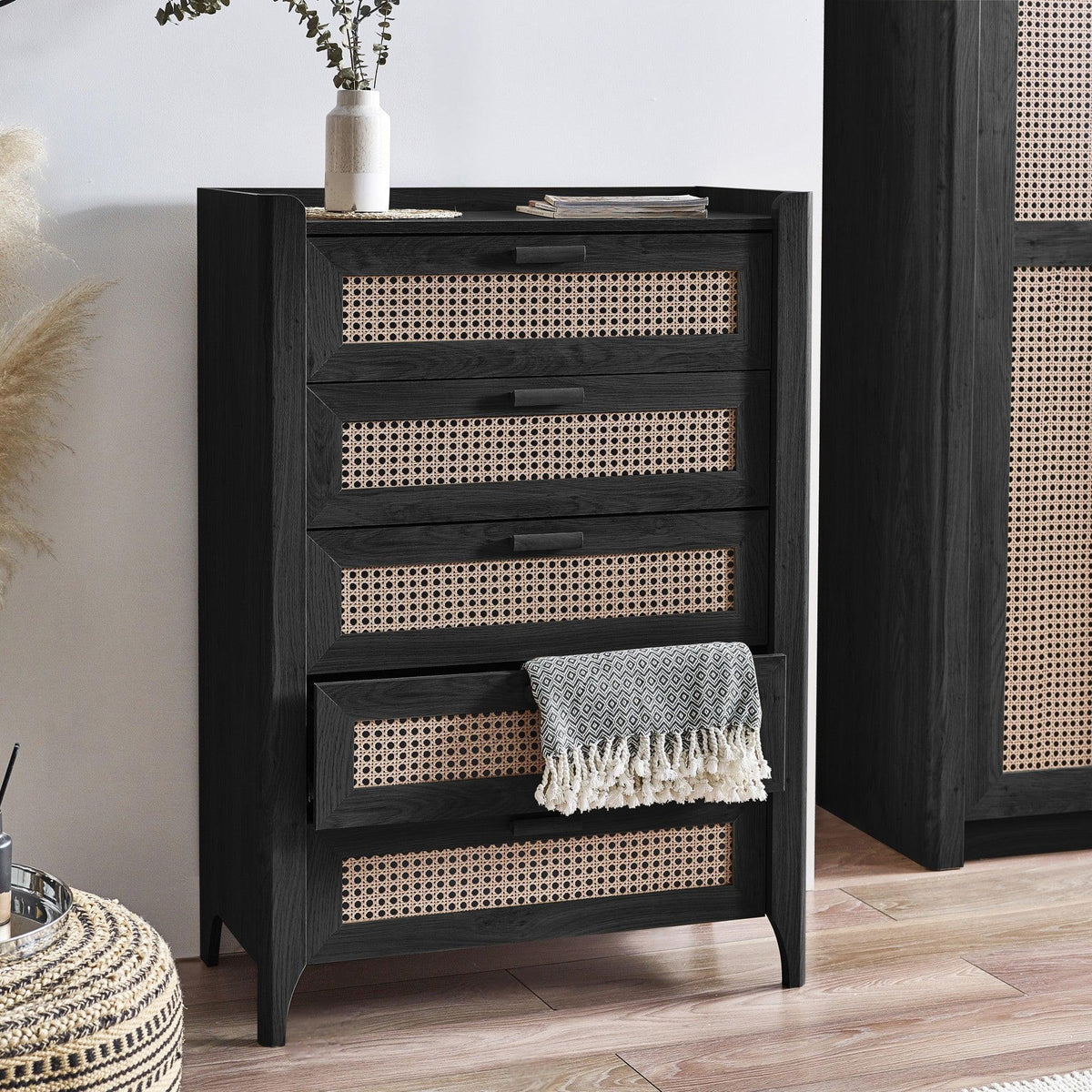 Black rattan effect 5 drawer chest with cane panels in modern bedroom interior
