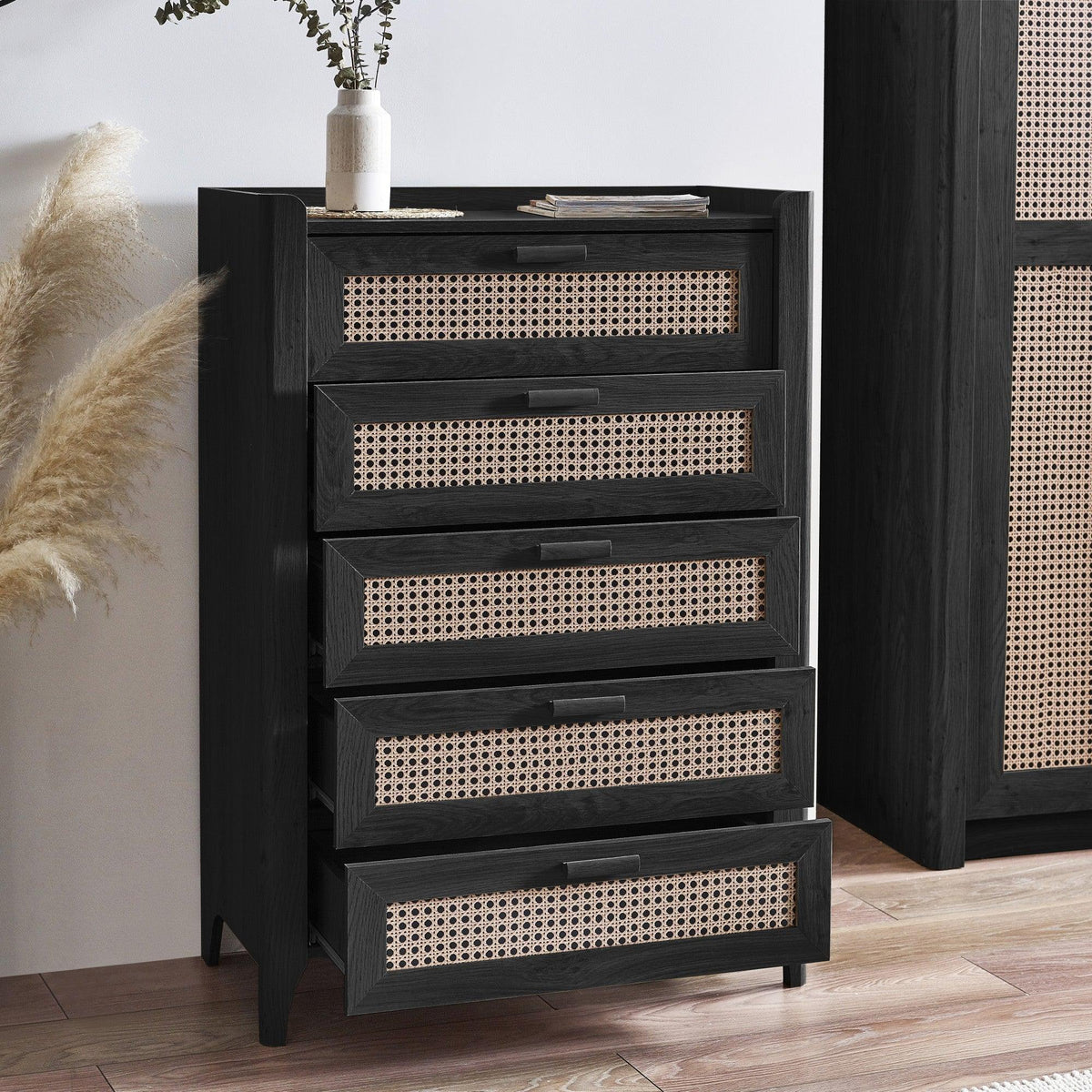 Sydney rattan effect black ash 5 drawer chest with woven fronts in a modern bedroom