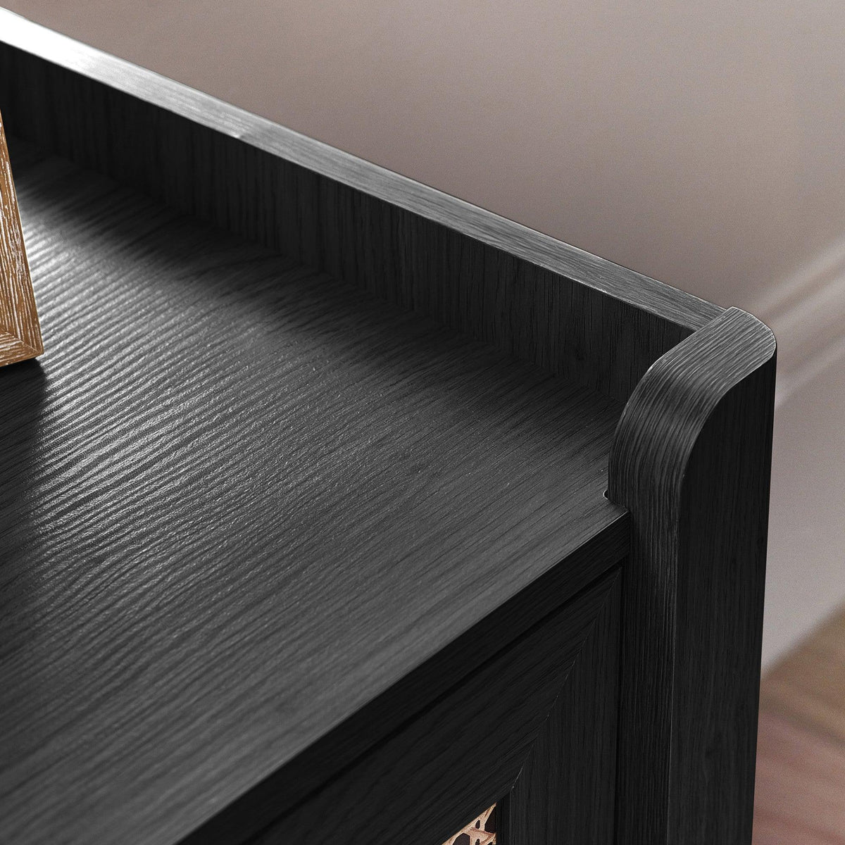 Close-up of black ash rattan effect wide chest top corner with wood grain detail