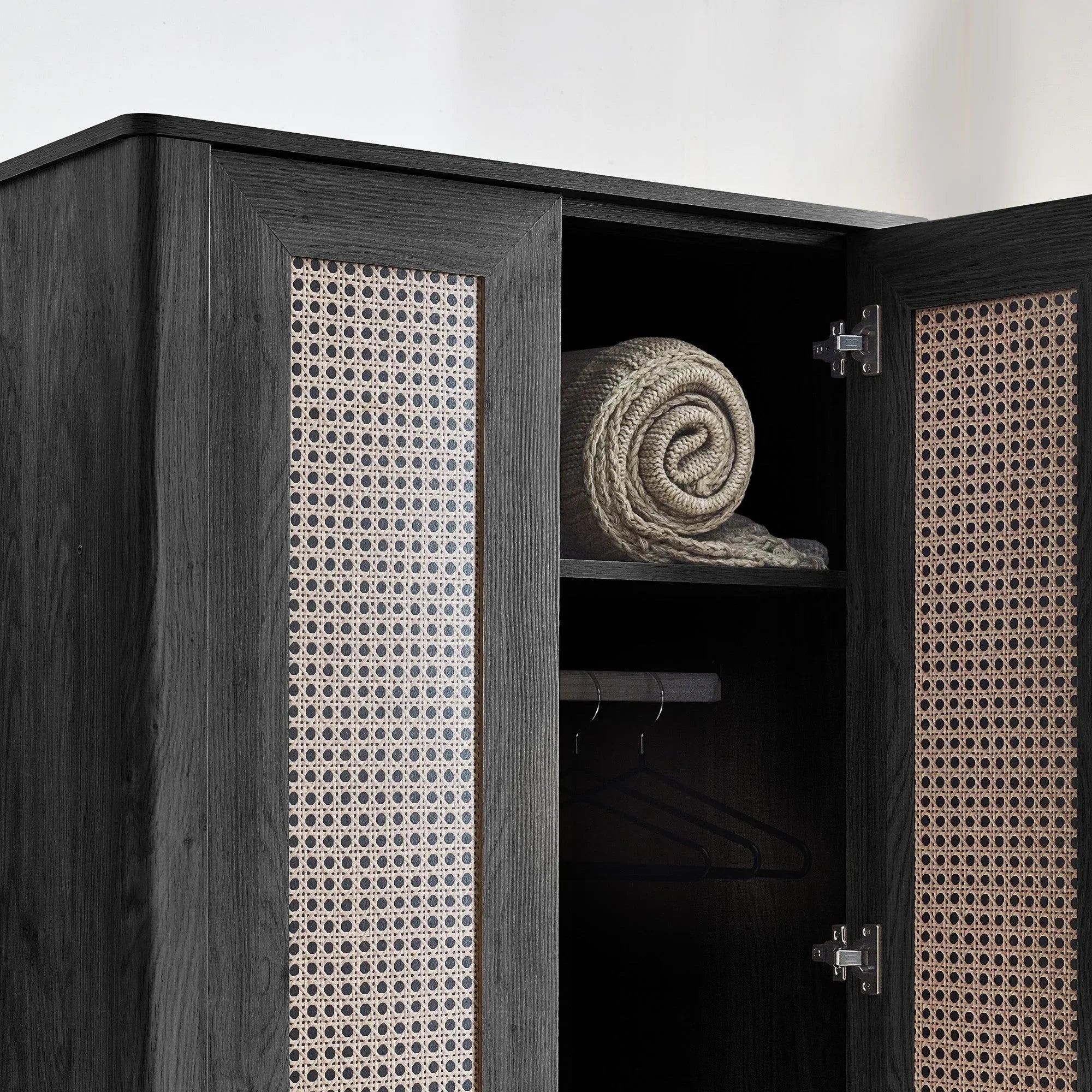 Open black ash rattan effect wardrobe with shelf, hanging rail, and rolled throw inside