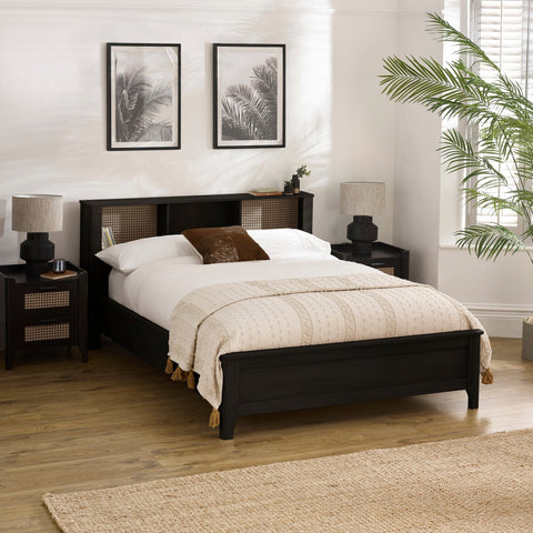 Black double bed with rattan inset storage shelves in headboard, cream bedding and brown cushion in bright bedroom