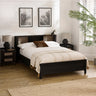 Black double bed with rattan inset storage shelves in headboard, cream bedding and brown cushion in bright bedroom