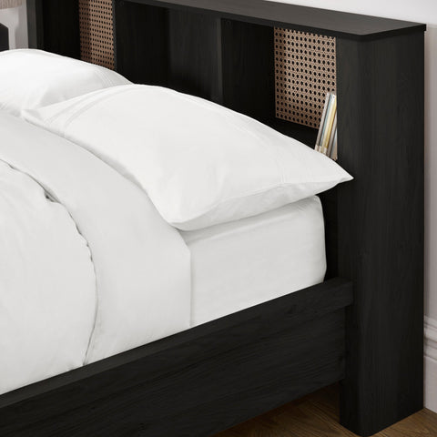 Close-up of black double bed's headboard showing rattan inserts and white bedding with grey throw