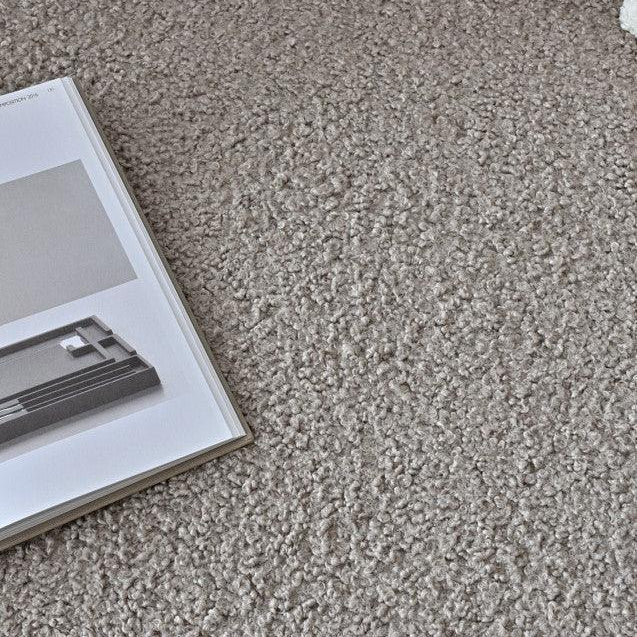 Beige boucle fabric sofa surface with book resting on seat cushion, close-up detail view
