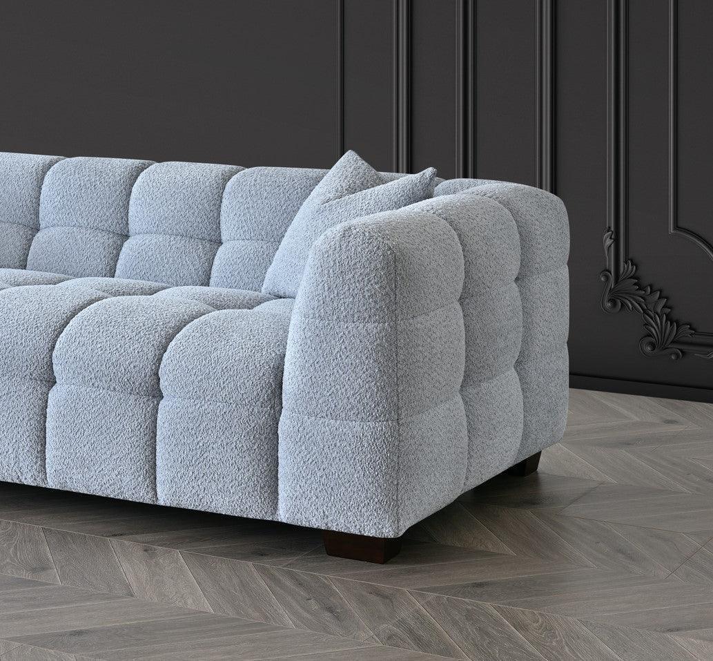 Modern grey fabric sofa with deep tufted upholstery and wooden legs in a contemporary lounge