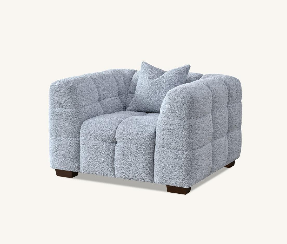 Light grey boucle armchair with quilted upholstery and matching cushion front angle view