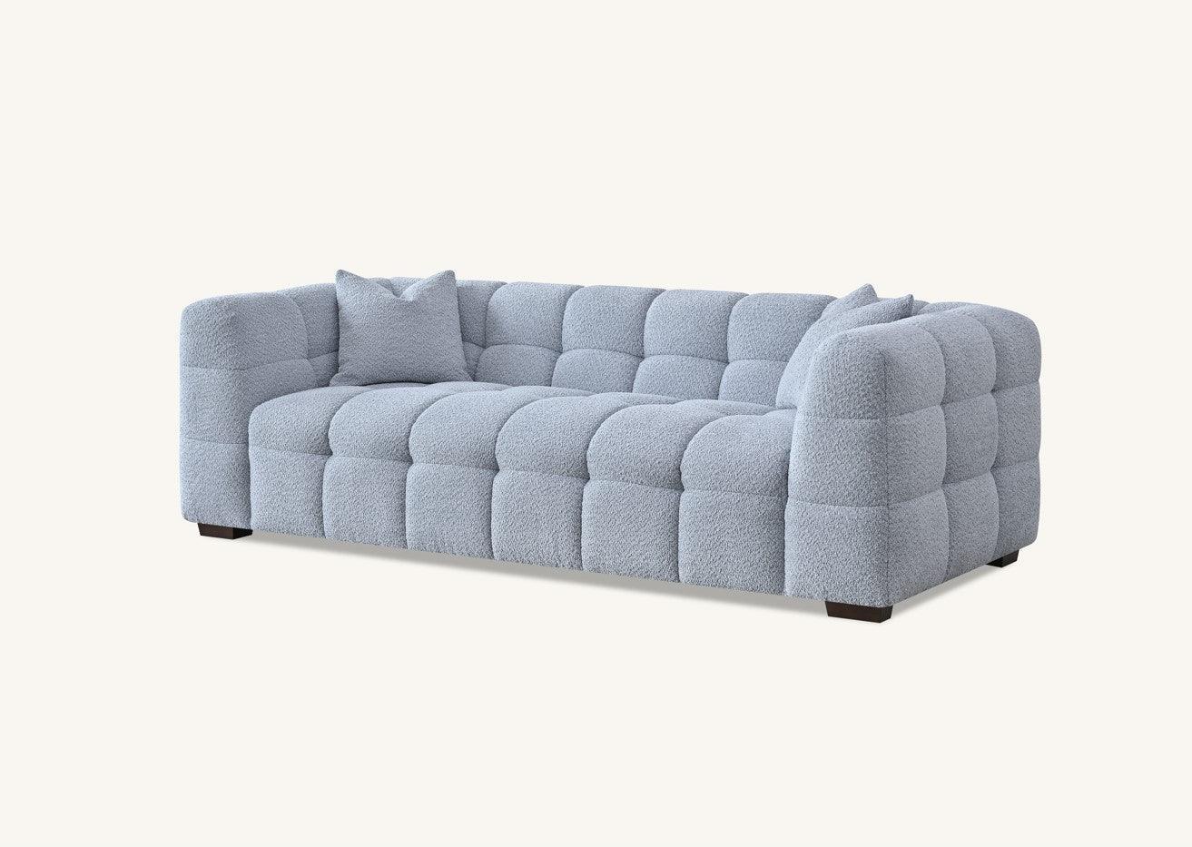 Light grey tufted sofa with plush upholstery and matching cushions, viewed from the front angle