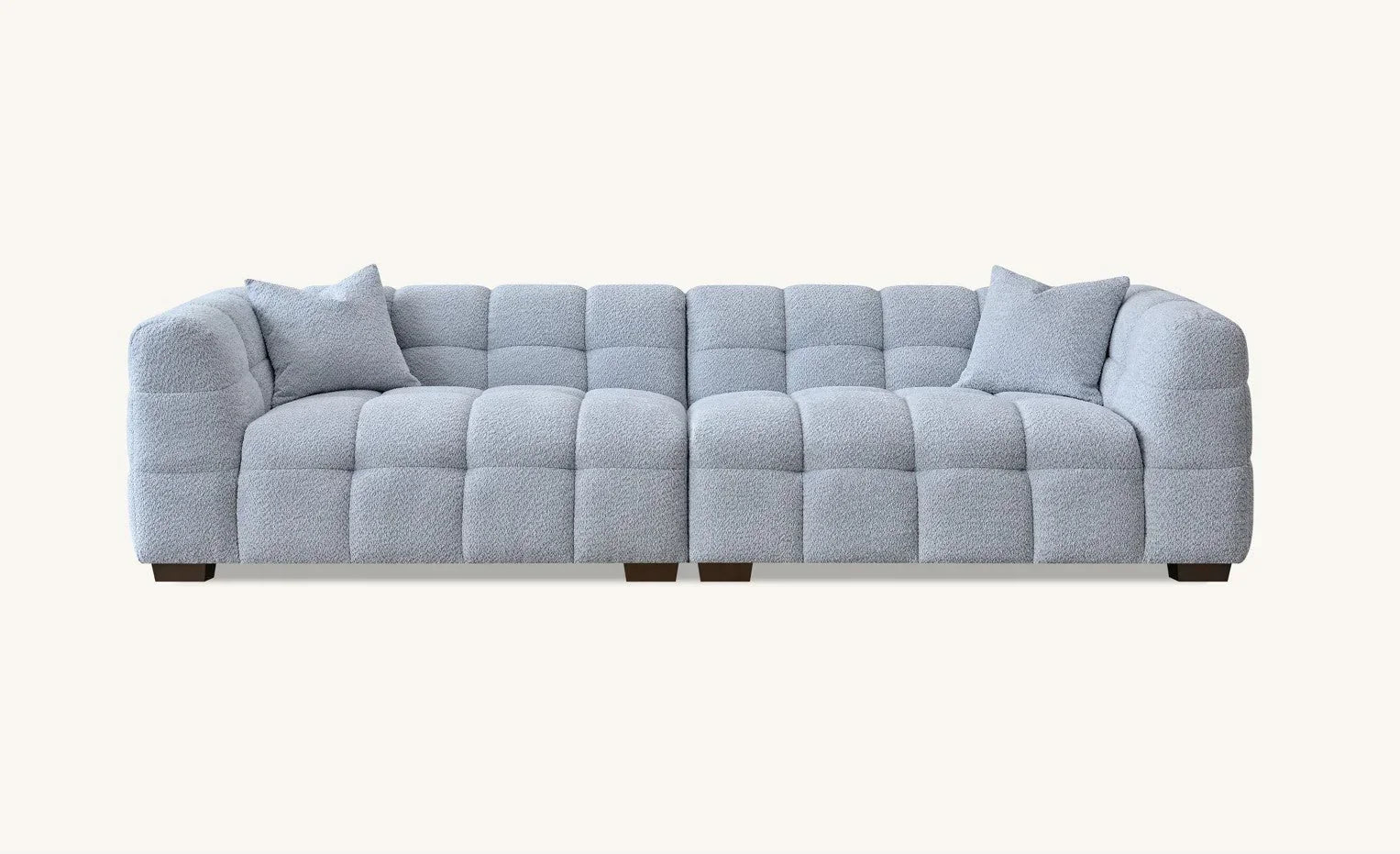 Light grey fabric sofa with square tufted design and two matching cushions, front view