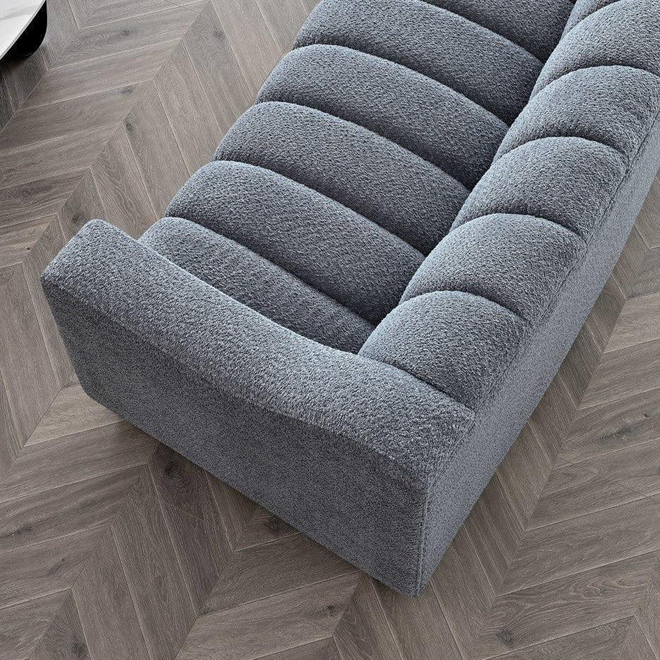 Grey textured fabric sofa with channel tufting on chevron wood floor