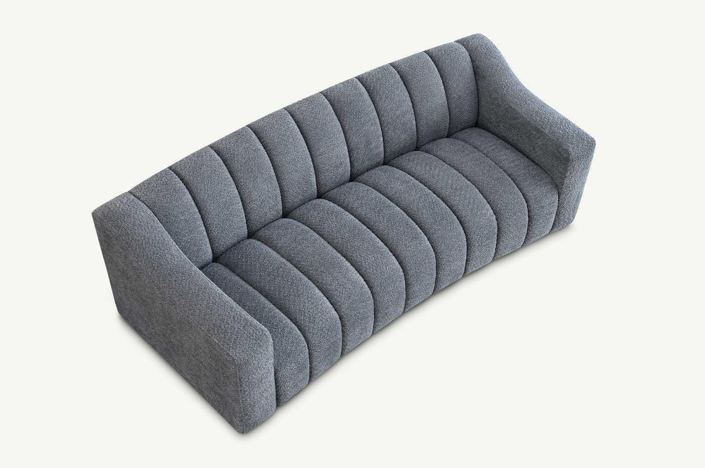 Curved grey fabric sofa with channel tufting and low armrests, angled top view