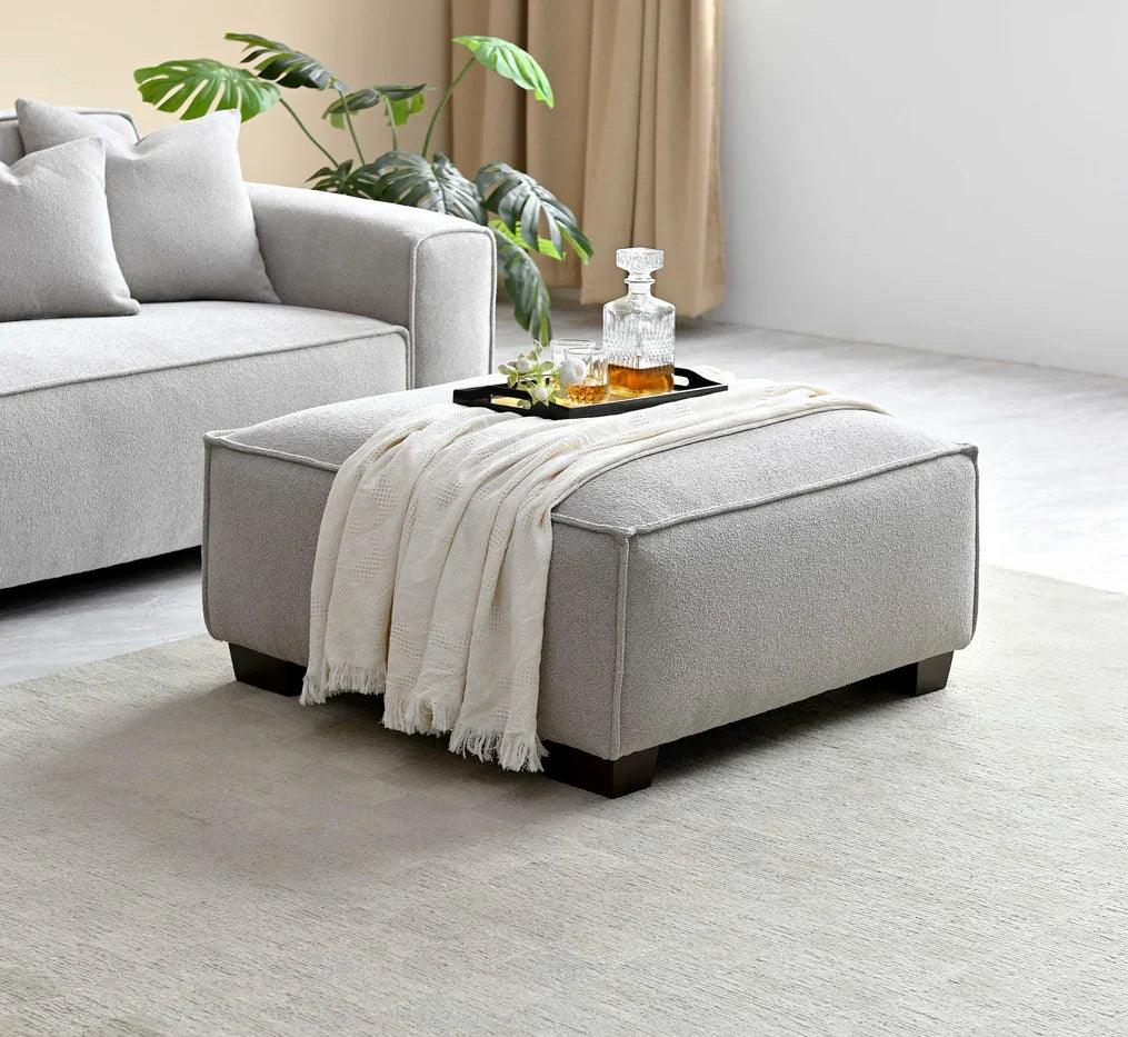 Light grey ottoman footstool with tray and throw beside sofa in modern living room