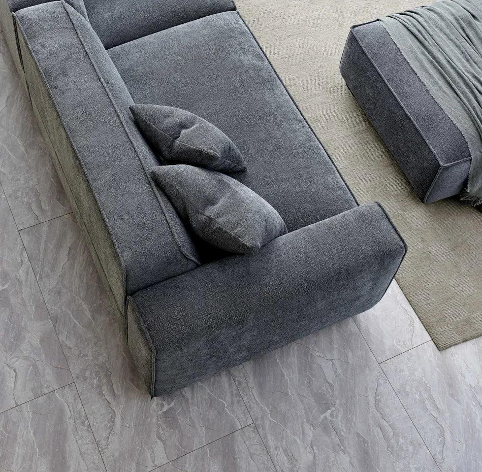 Grey fabric sofa with matching cushions and ottoman on marble tile flooring