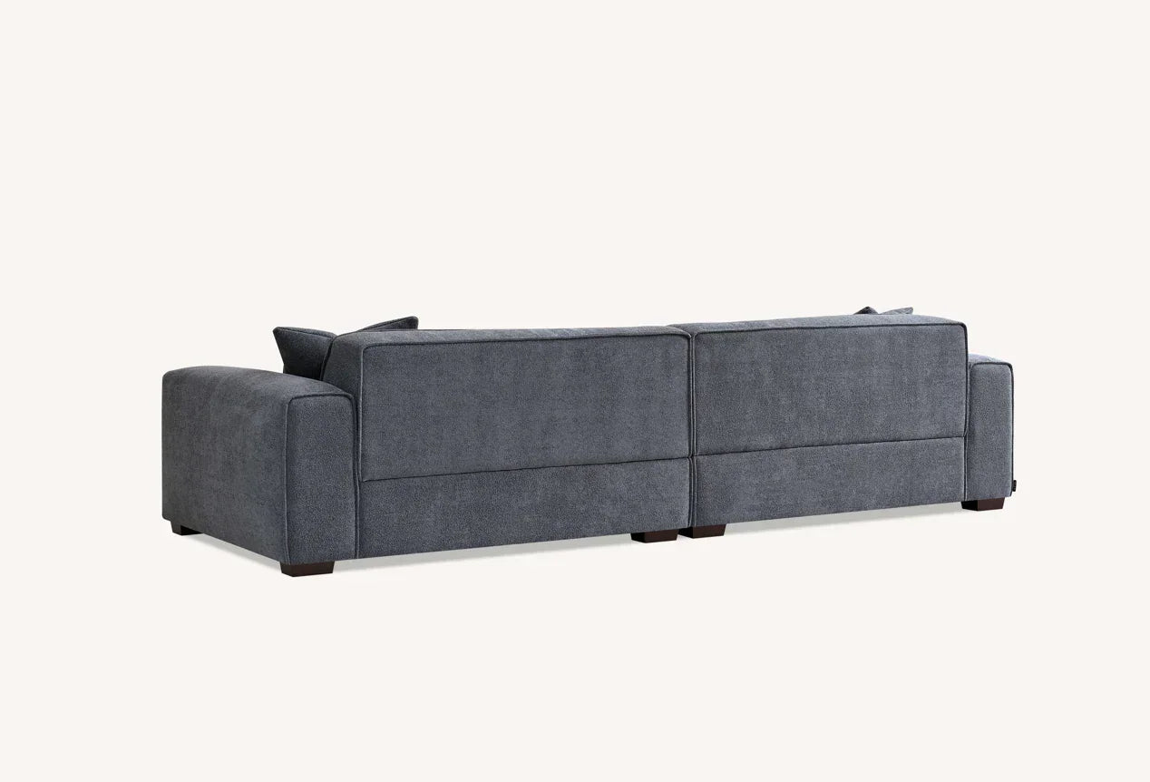 Rear view of grey fabric sofa with low backrest and wide armrests on short legs
