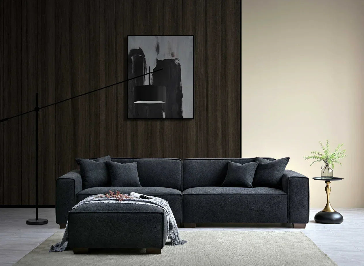 Dark grey corner sofa with matching ottoman, scatter cushions, and side table in modern living room