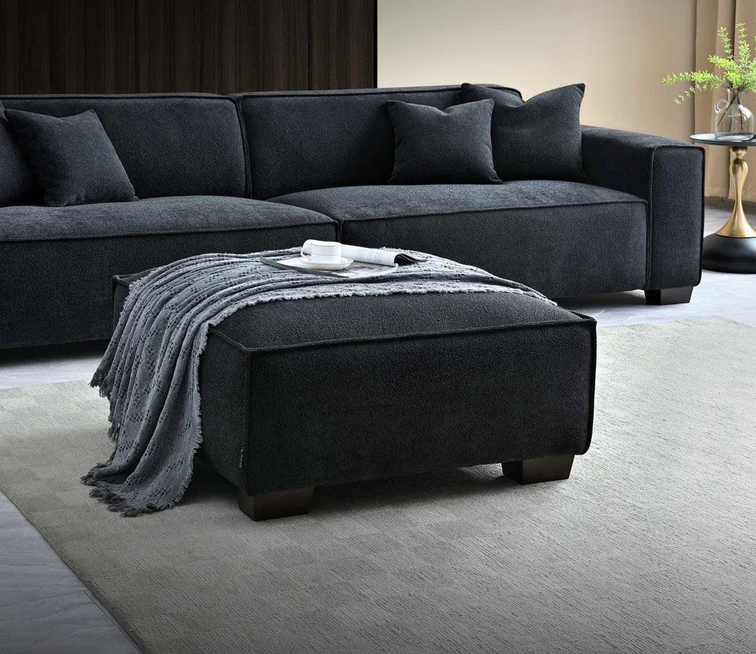 Dark grey fabric corner sofa with matching ottoman and throw in modern living room
