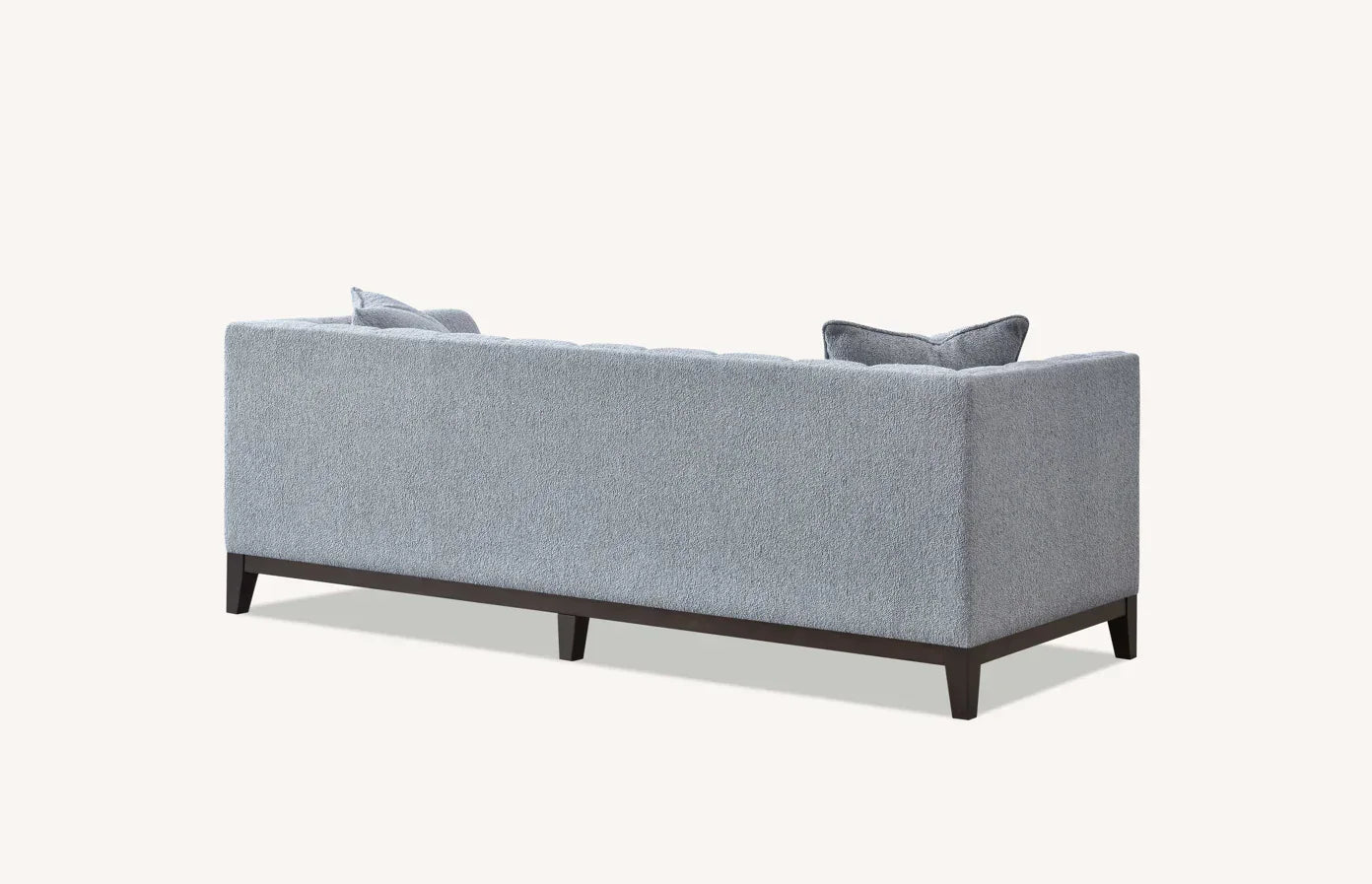 Back view of grey fabric sofa with dark wood legs and two matching cushions