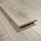 Silver oak wood flooring plank on matching laminate floor, showcasing grain and texture