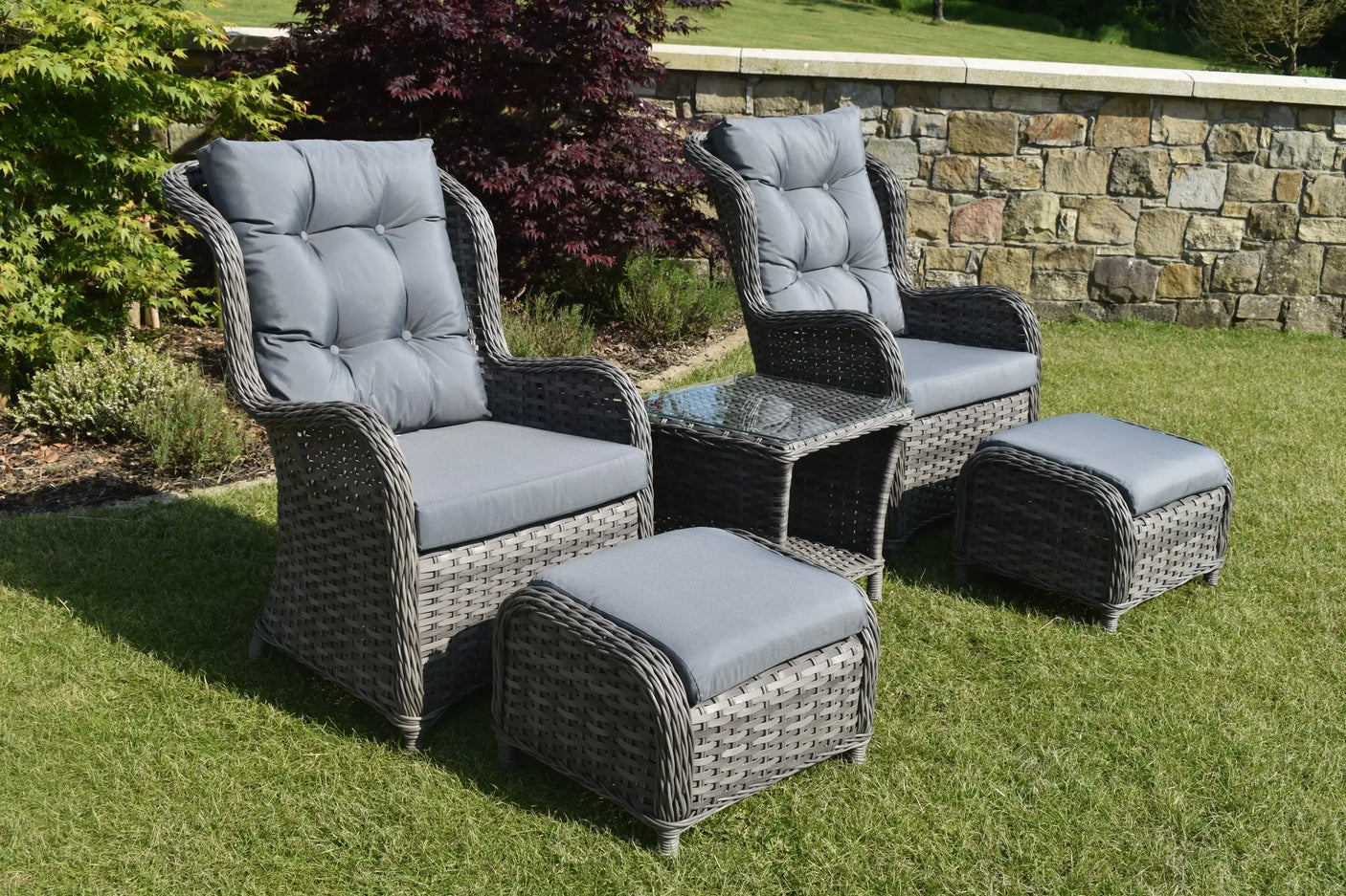 Grey rattan garden bistro set with two cushioned chairs, glass table, and two footstools