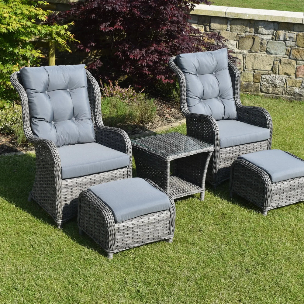 Grey rattan bistro garden set with two armchairs, ottomans and glass top table on lawn