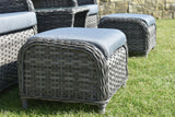 Grey rattan garden seating set with blue cushions on grass, close up of ottomans and armchair