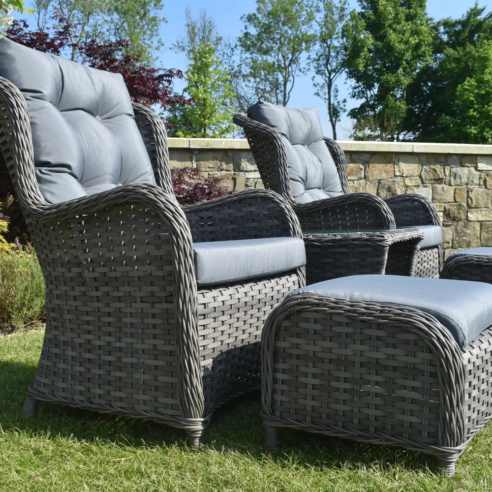 Grey rattan garden bistro set with cushioned chairs and ottomans on grass