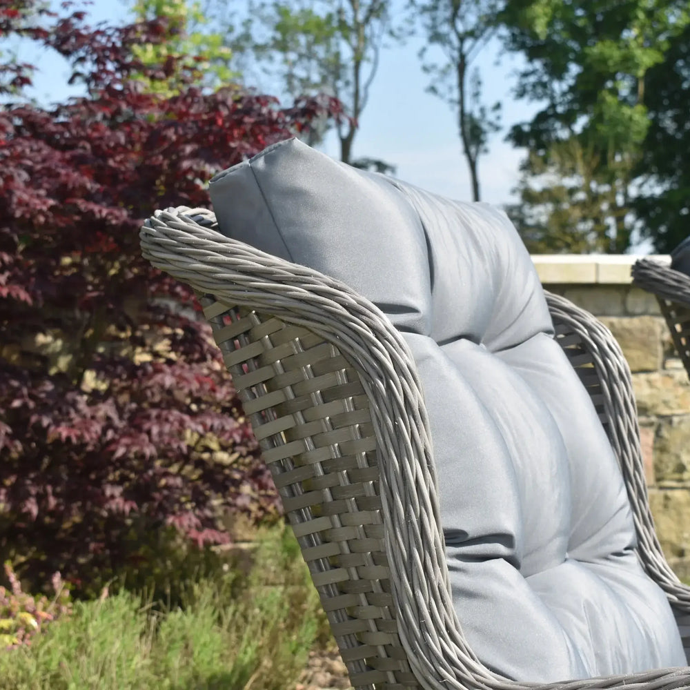 Grey rattan garden chair with padded cushion in outdoor patio setting