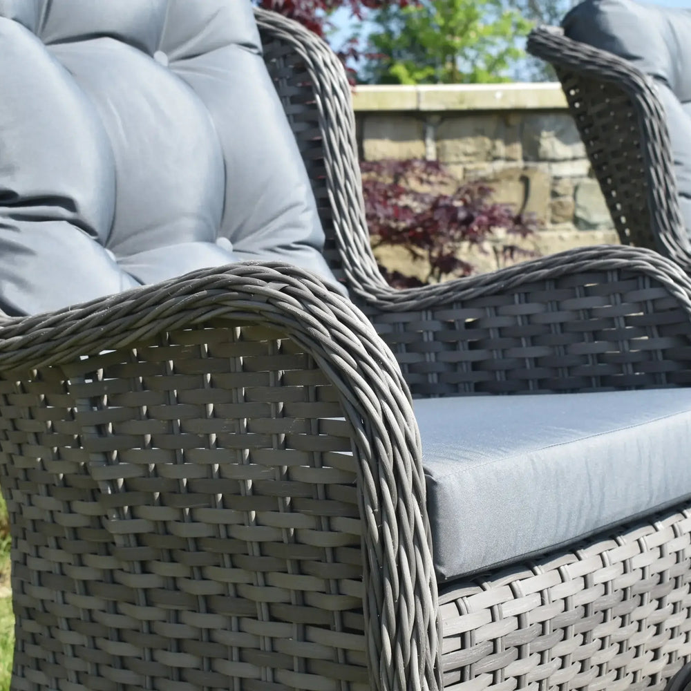 Grey rattan garden chair with padded seat and backrest in outdoor setting