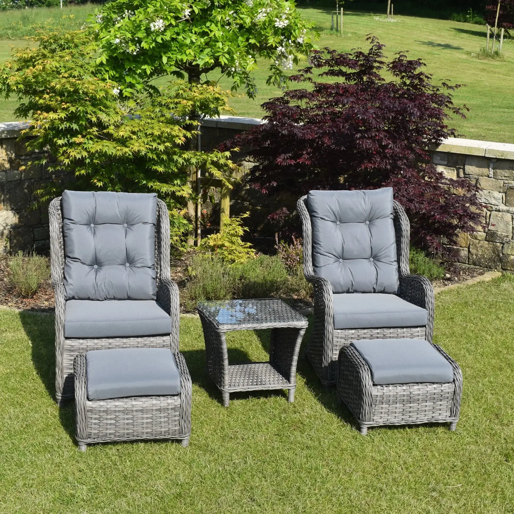 Grey rattan bistro garden set with two cushioned chairs, ottomans, and glass-top table on lawn