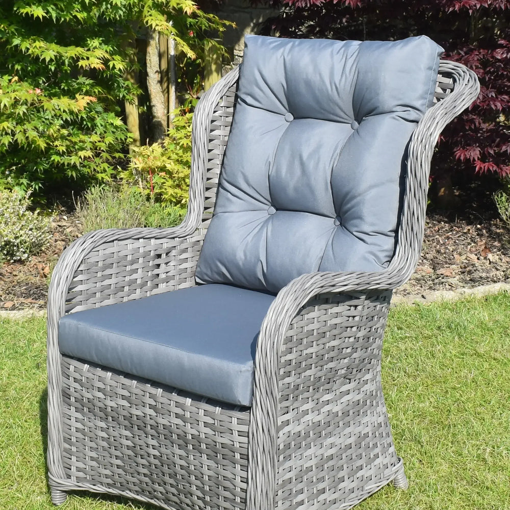 Grey rattan garden armchair with blue padded cushions on lawn