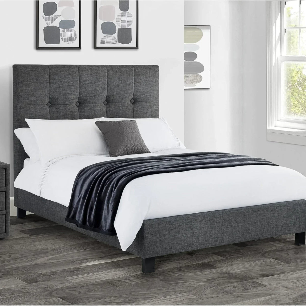Grey upholstered bed frame with tall headboard, white bedding, and bedside table in modern bedroom