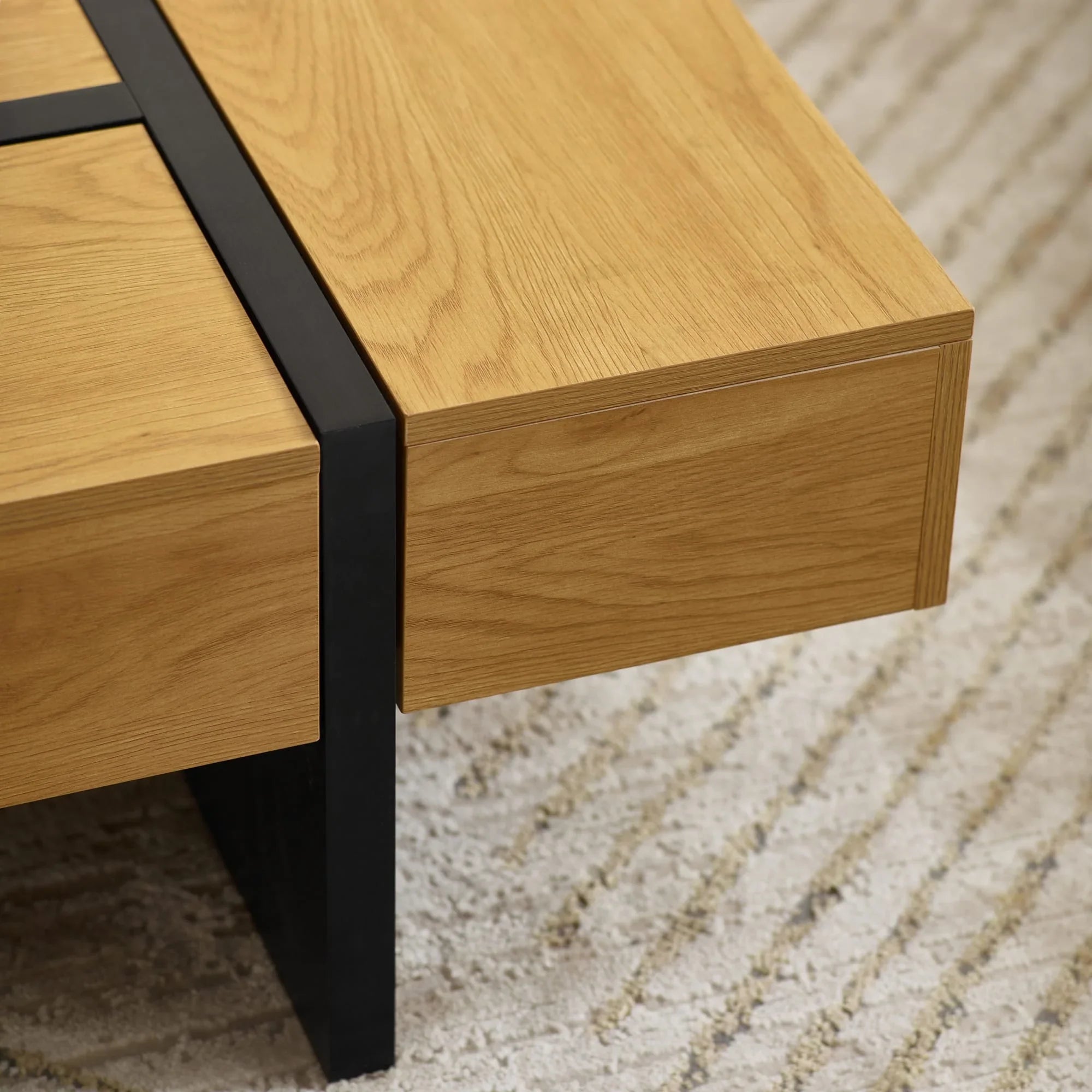 Oak coffee table with black metal leg on textured beige rug, close-up corner view