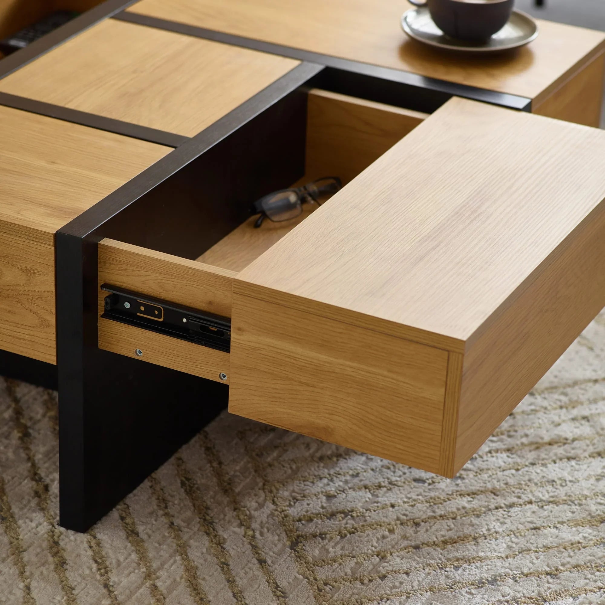 Oak coffee table with black metal frame and open storage drawer on textured rug