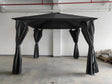 Black garden gazebo with canopy roof and tied curtains, shown in indoor warehouse setting