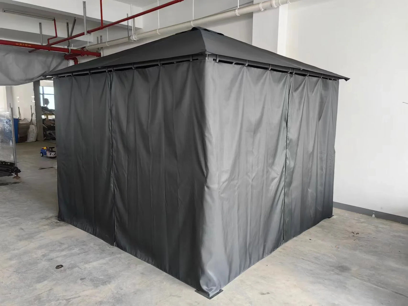 Grey outdoor gazebo with full curtain enclosure in indoor setting