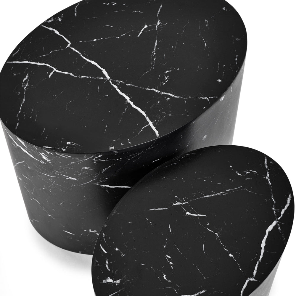 Close-up top view of two black oval nest tables with white marble veining on white background