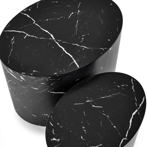 Close-up top view of two black oval nest tables with white marble veining on white background