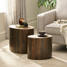 Two dark wood oval nest tables with candle and plant, beside beige fabric sofa in room setting